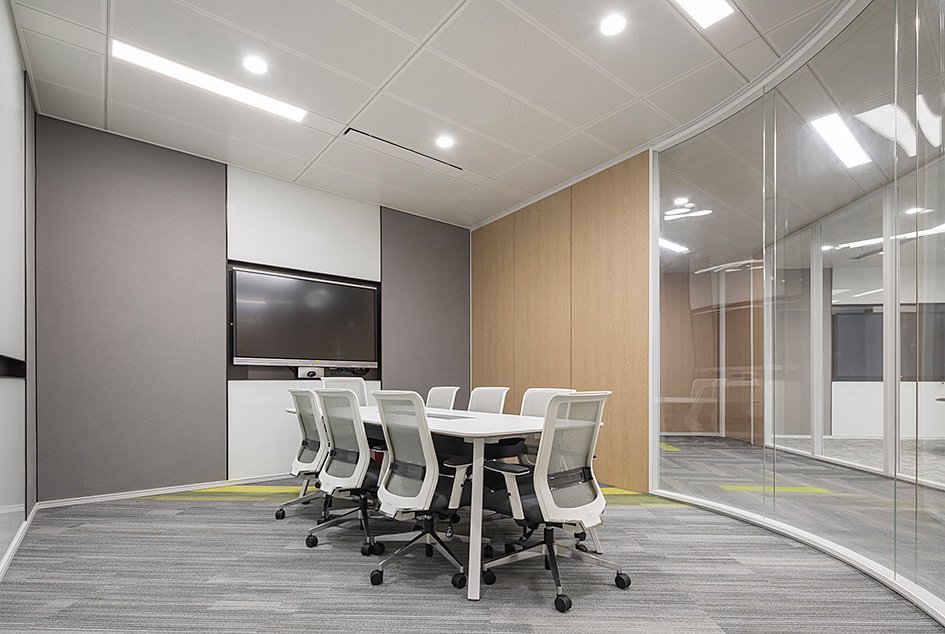 Custom curved panoramic glass partition system for high-end conference rooms with wood veneer accent walls.