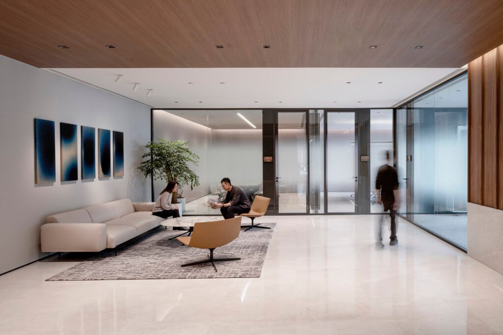 Modern office reception area using floor-to-ceiling panoramic glass partitions to maximize natural light and spatial transparency.