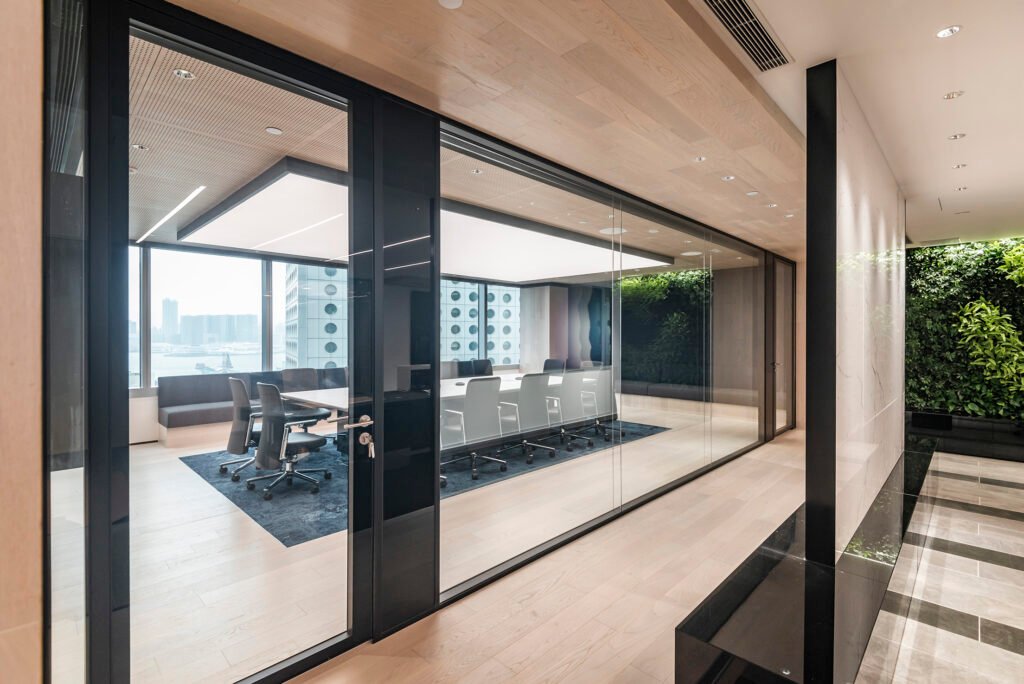 High-end acoustic glass partition wall for executive boardrooms featuring black frames and integrated vertical green wall.
